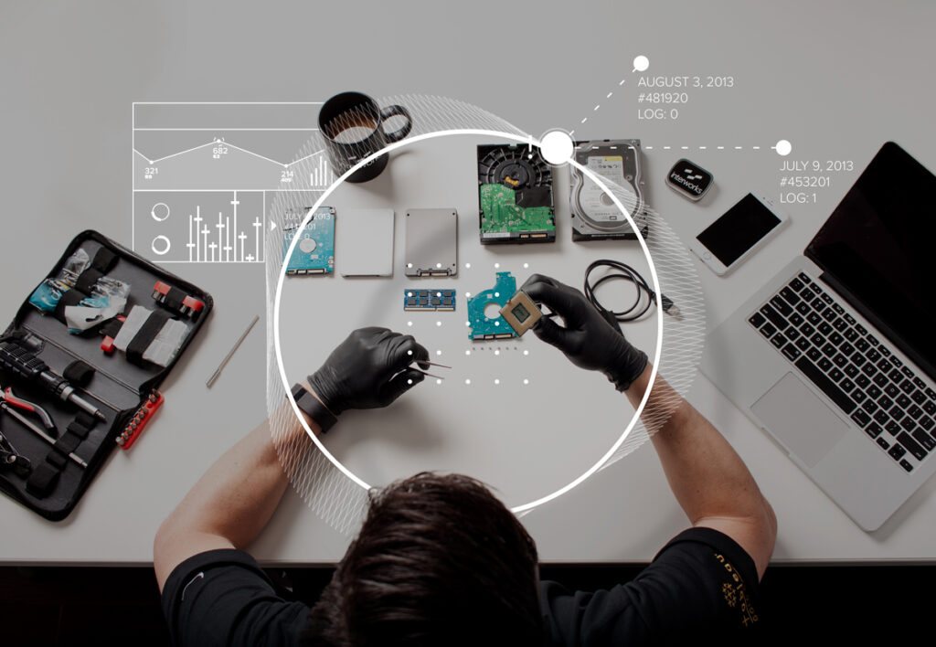 Overhead view of a forensic examination — storage drives, a phone, and tools laid out on a workbench